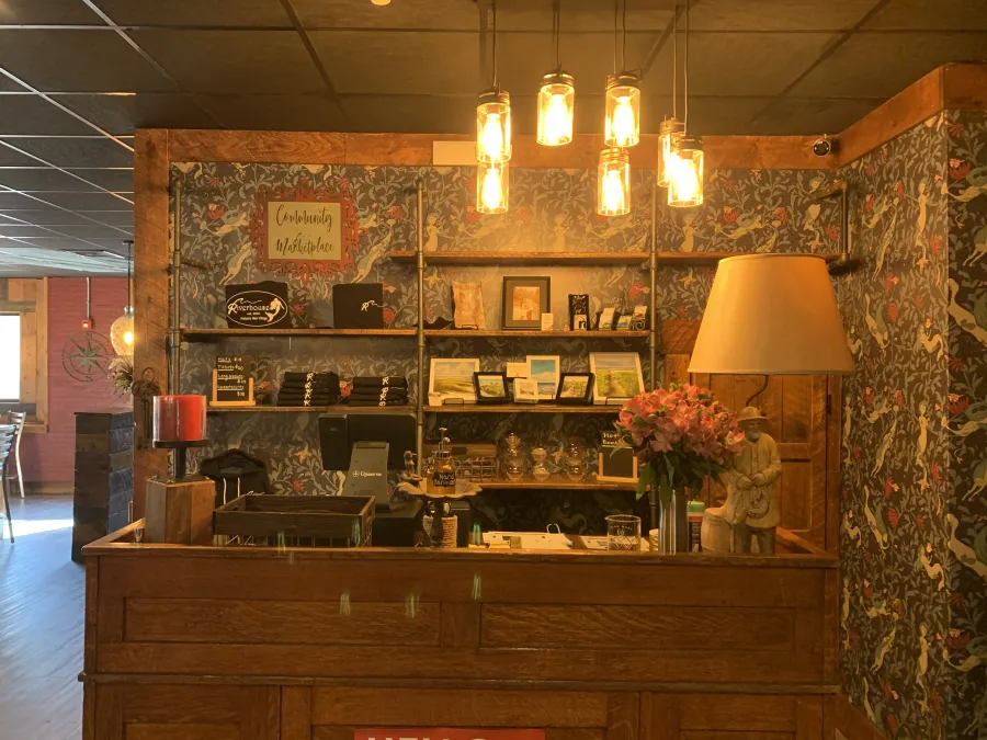 Warm, lantern-lit interior of Riverhouse with patterned wallpaper and wood shelving